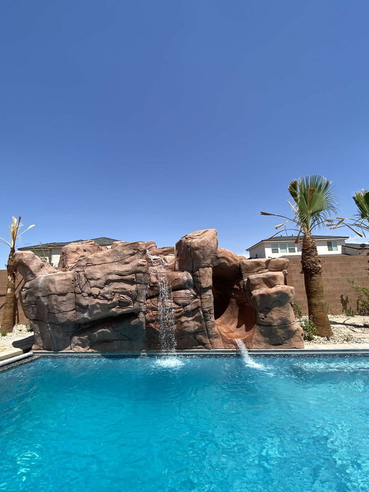 Rock-style waterfall and slide at the edge of a swimming pool